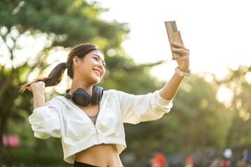Portrait of smiling cheerful beautiful pretty asian woman clean fresh healthy white skin posing smile look at camera making live selfie on smartphone at green park