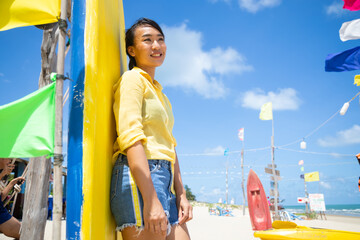 Cute and beautiful girl standing in front of a surfboard on the beach. Vacation trip summer holiday.