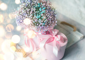 delicate bouquet with pink small flowers and gift box on a wooden white tray. Soft focus, light background
