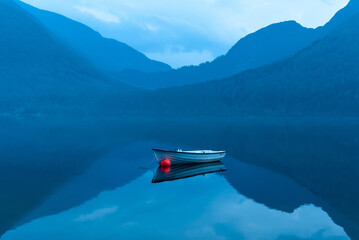 small rowing boat reflects in the water in the blue hour