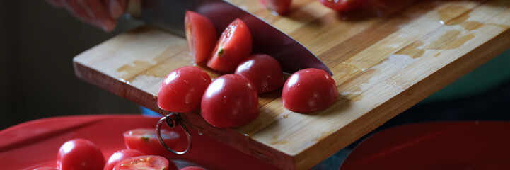 Woman cutting tomatoes on wooden board and and putting on plate