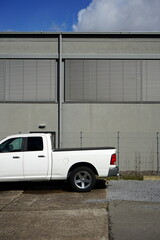 Weißer amerikanischer Pick-up mit Doppelkabine vor moderner grauer Architektur mit Jalousien als...