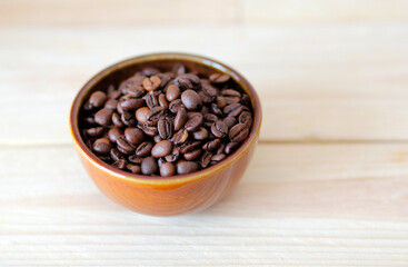 Fototapeta premium close-up of brown coffee beans in a bowl, coffee beans background, coffee beans in a bowl on wooden table, space for text, roasted coffee beans