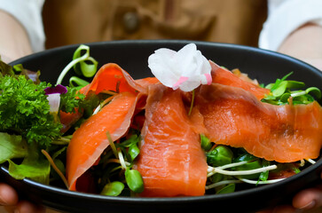 Healthy food meal cooked Fresh Salmon Salad served with Cucumber Roe and Lettuce bean sprouts Tomato garnished with salali and sesame oil sauce decorated with flowers