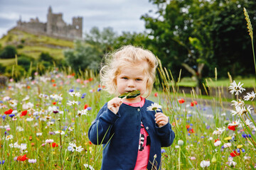 Cute toddler girl with Irish cloverleaf lollipop with Rock of Cashel castle on background. Happy...