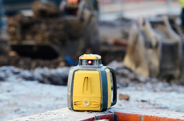 Rotating laser surveying equipment at building construction site with blurred background