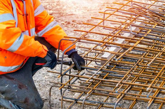 Steel fixer assembling reinforcement cage off rebars. Selective focus