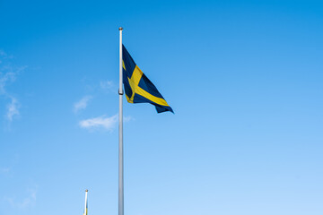 Swedish flag on a flagpole waving in the wind.