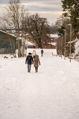 People taking sunday walk in a snowy park.