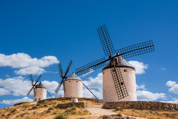 Fototapeta na wymiar Three of windmills of Consuegra on the hill with blue sky and white clouds (Spain)