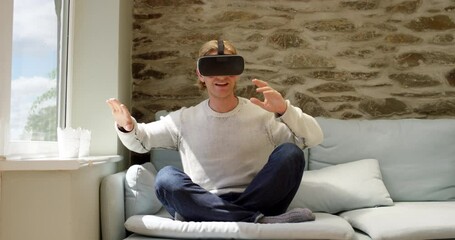 Virtual reality, glasses and man on sofa with gaming user experience, cyber vision and metaverse at home on future technology. 3D, vr video games and gamer experience on high tech in his living room