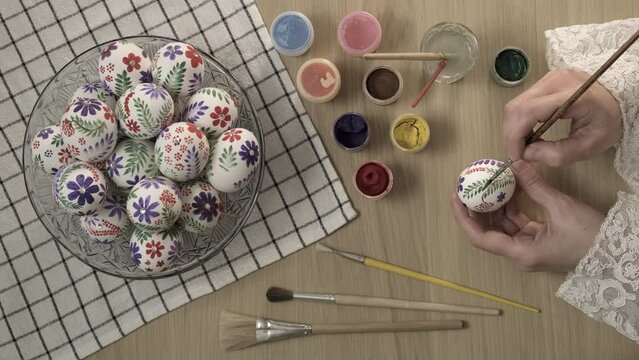 Easter Eggs. Master class on painting eggs for the holiday. Female hands painting with paints and brush on an Easter eggs at home, vertical video