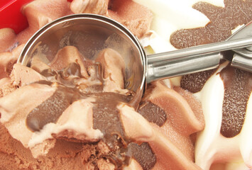 Ice cream scoop on chocolate and vanilla ice-cream background.