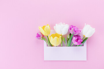 Envelope with spring tulip flowers on pink background for Mothers day greeting message.