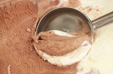 Chocolate and vanilla ice-cream with metal scoop close up.