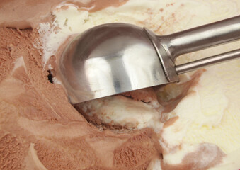 Chocolate and vanilla ice-cream with metal scoop close up.