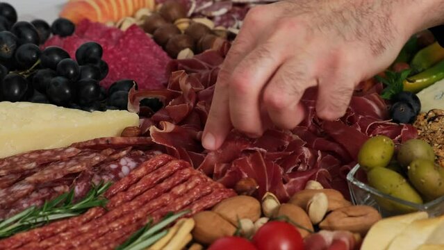 Tasting Prosciutto from meat platter. Hand takes meat from meat plate. Antipasto