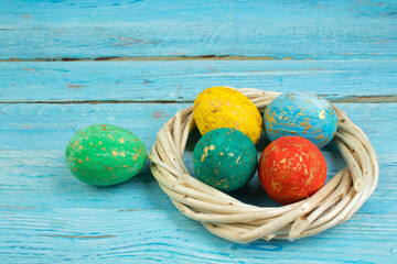 Happy Easter.Colorful shiny eggs on wooden table background. wreath woven from the vines. Copy space for text. Top view.