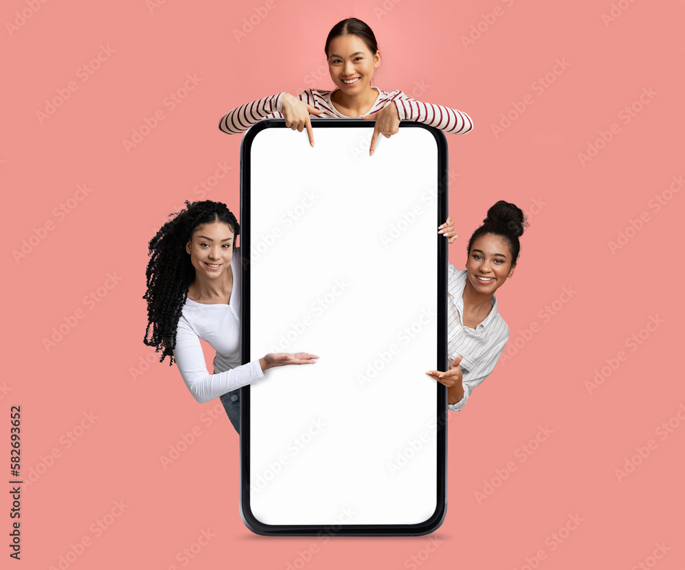 Poster check this. three cheerful females pointing at big smartphone with blank screen