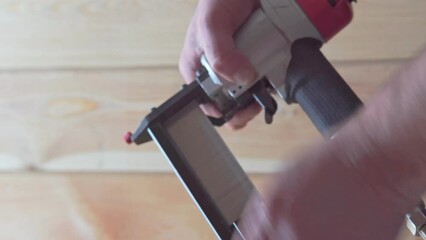 Video close up unrecognizable man hands refilling and setting up pneumatic nail gun stapler, nailer for wood work. Clipping and scoring metal nails and staples. Builder occupation, civil engineer, 4k