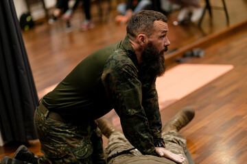 A 40-year-old bearded military medic demonstrates how he applies hand pressure to a wounded limb to...