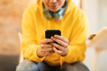 Fototapeta premium Cropped Shot Of Teenager Guy Using Smartphone Sitting At Home