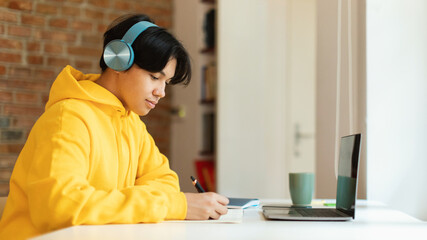 Korean Teenager Boy At Laptop Taking Notes Learning At Home
