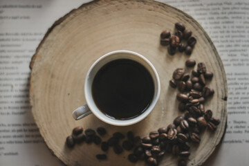 morning coffee, coffee beans and cup on wood and books
