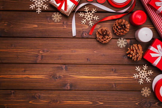 Christmas, New Year's corner composition on brown wooden boards made of cones, snowflakes, candles, gifts in wrapping paper with ribbon bows. Frame, layout, postcard.