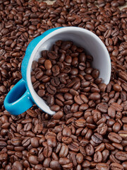 Cup of steaming hot coffee with coffee beans, coffee grinder, and coffee beans bag in background.