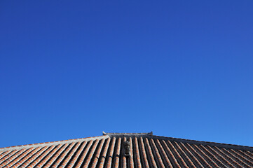 沖縄県小浜島赤瓦の屋根とシーサーと青空