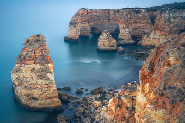 Naklejka na ściany i meble Cliffs, rock formations and natural arches in la Marina beach at sunset in the Algarve region near Albufeira and Portimao cities. Portugal.