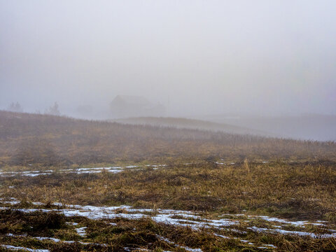 barn on a hill covered by mist in the morning