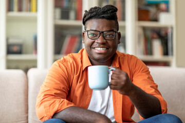 Happy young black man enjoying morning coffee at home