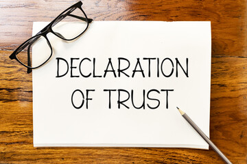 Declaration of trust text on blank notebook paper on wooden table with pencil and glasses aside....