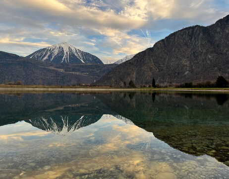 Mirror reflection of a snow-covered mountain in a lake with mountain water in Martigny, Switzerland