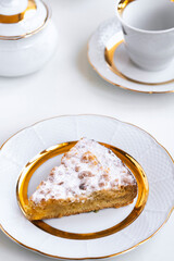 Piece of delicious homemade pie on white plate, cup and teapot