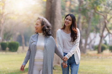 Adult daughter holding her elderly mother hand with love and walk together