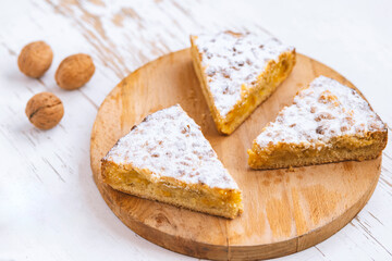 Pieces of apple pie with walnuts on wooden background