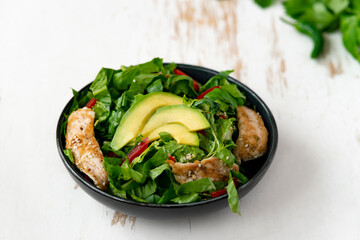 chicken salad with avocado in a black bowl. Healthy food