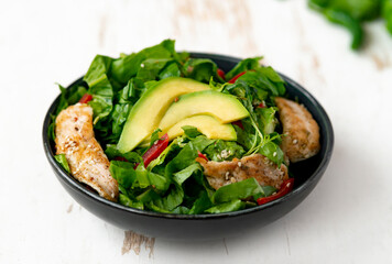 chicken salad with avocado in a black bowl. Healthy food