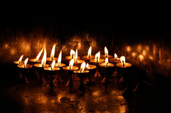 Esquina a oscuras iluminada por las llamas de las velas en peque&ntilde;as copas doradas, que dan un reflejo dorado en las pareces