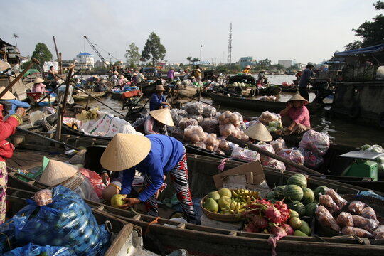 Mercado flotante de Cai Rang, Vietnam, delta del Mekong, muchas pequeñas barcas con frutas y verduras venden apiñadas la mercancía con compradores con gorros típicos 