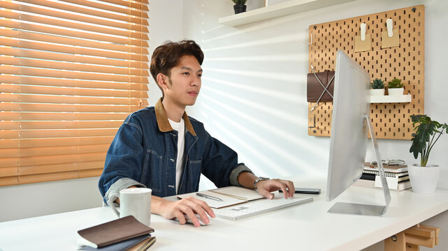 Smiling man freelancer looking at computer monitor, working from home, enjoying distant job