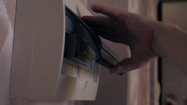 Hand switching power switch on a fusebox. Close up of electrician checking fuse box knob 