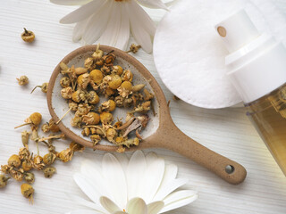 Bottle of chamomile toner for face or hair and dry chamomile flowers