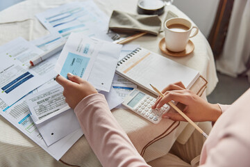 Cropped unrecognizable faceless woman calculates expenses expenditures uses calculator poses at...