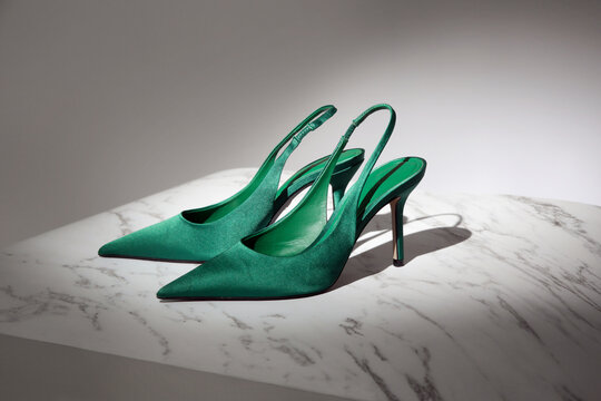 Creative studio shot of green satin slingbacks heels with the classy pointed toe, product photography