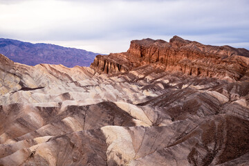 Fototapeta na wymiar Zabriskie Point. It is a part of the Amargosa Range located east of Death Valley National Park in California, United States. One Man on the Top of Mountain.