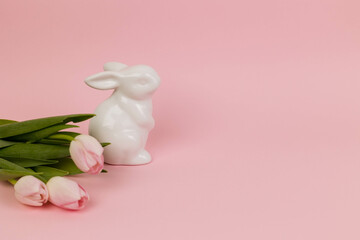 Easter card with pink tulips and a toy rabbit on a pink background, copy space